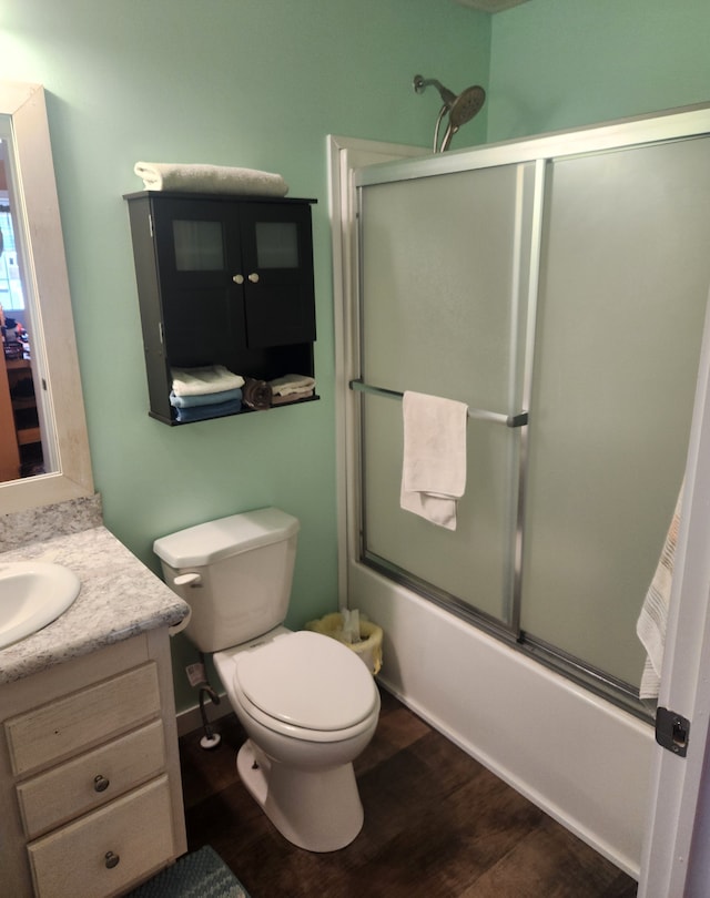 bathroom featuring vanity, enclosed tub / shower combo, toilet, and wood finished floors