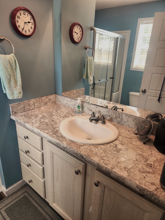 bathroom featuring vanity, toilet, and a shower stall
