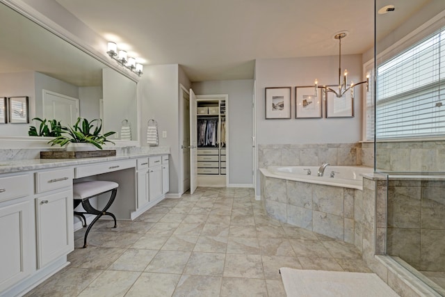 bathroom with a garden tub, vanity, marble finish floor, a walk in closet, and a notable chandelier