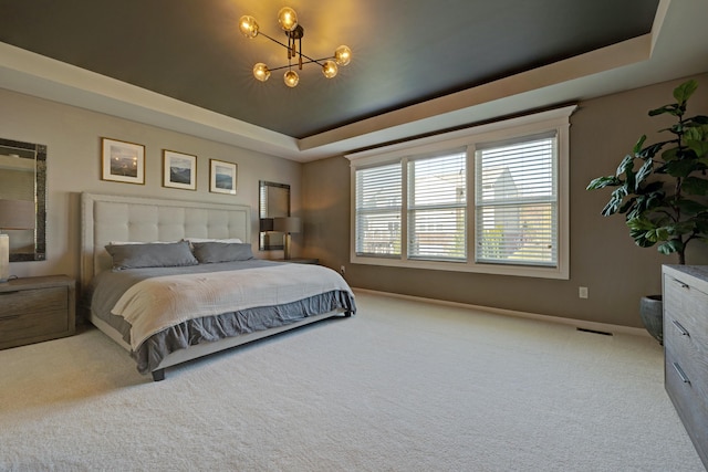 carpeted bedroom featuring a tray ceiling, a chandelier, baseboards, and visible vents