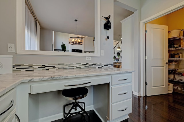 kitchen with an inviting chandelier, light stone counters, white cabinetry, tasteful backsplash, and dark wood-style floors