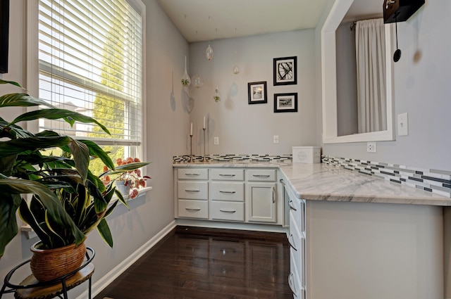 kitchen featuring white cabinets, light stone counters, baseboards, tasteful backsplash, and dark wood-style floors