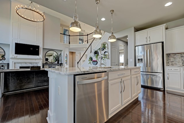 kitchen with white cabinets, dark wood-style flooring, light stone counters, a sink, and stainless steel appliances