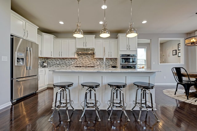 kitchen with appliances with stainless steel finishes, under cabinet range hood, dark wood-style floors, and tasteful backsplash