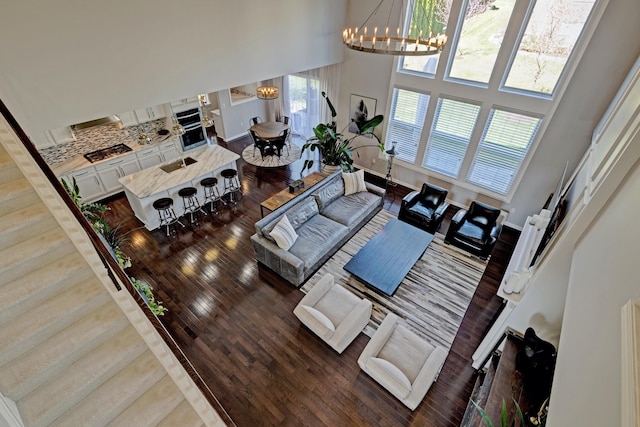 living room featuring plenty of natural light, a towering ceiling, wood finished floors, and a chandelier
