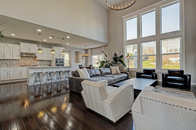 living area featuring an inviting chandelier, recessed lighting, a towering ceiling, and dark wood-type flooring