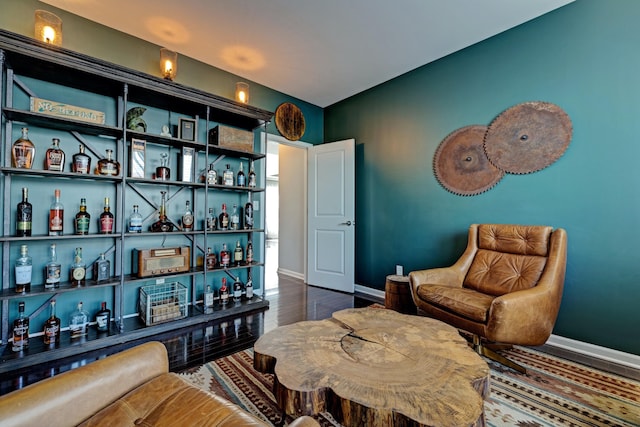 sitting room featuring baseboards, a dry bar, and wood finished floors