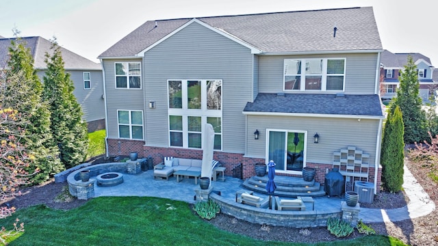 back of property with a patio area, brick siding, cooling unit, an outdoor living space with a fire pit, and a yard