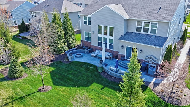 rear view of house with a lawn, a shingled roof, and a patio area