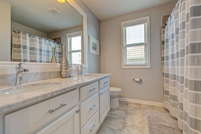bathroom with baseboards, double vanity, toilet, and a sink