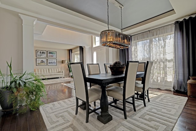 dining room featuring decorative columns, hardwood / wood-style flooring, and a chandelier