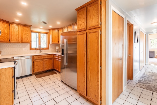 kitchen featuring decorative backsplash, visible vents, appliances with stainless steel finishes, light tile patterned floors, and a sink
