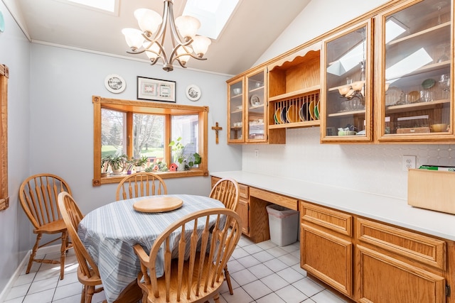 dining room with a chandelier, ornamental molding, light tile patterned floors, and vaulted ceiling with skylight