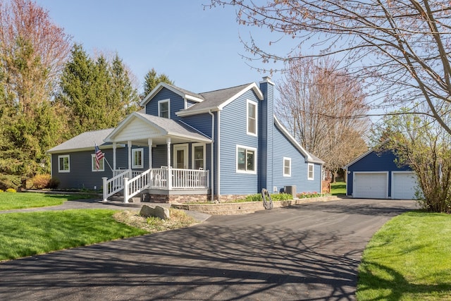 view of front of house with covered porch, a chimney, an outbuilding, a garage, and a front lawn