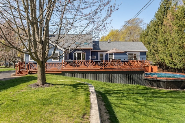 back of property with a lawn, a deck, and a swimming pool