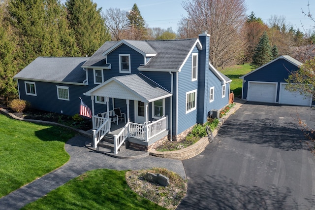 bungalow-style home featuring an outdoor structure, a garage, a front lawn, covered porch, and a chimney