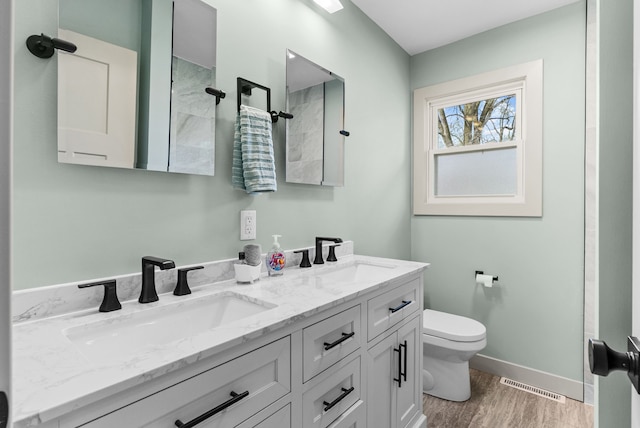 5857 Berkley Dr, Waterford, MI 48327 - bathroom with toilet, wood finished floors, double vanity, baseboards, and tiled shower