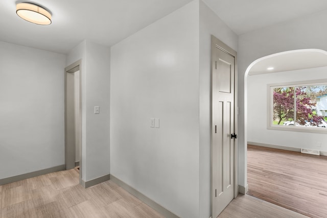 5857 Berkley Dr, Waterford, MI 48327 - corridor featuring light wood-type flooring, arched walkways, and baseboards