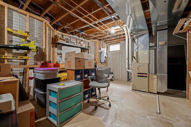 basement featuring heating unit and brick wall