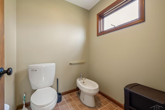 half bathroom featuring baseboards, tile patterned flooring, toilet, and a bidet