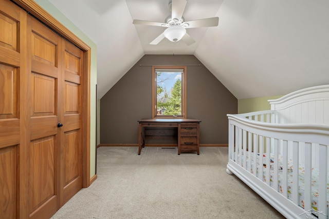 bedroom with lofted ceiling, baseboards, light colored carpet, a nursery area, and a ceiling fan