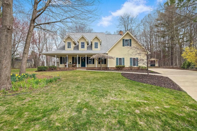 view of front of house with a front lawn, covered porch, roof with shingles, a chimney, and driveway