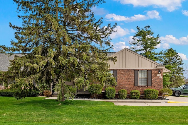 view of front of home featuring board and batten siding, brick siding, and a front yard