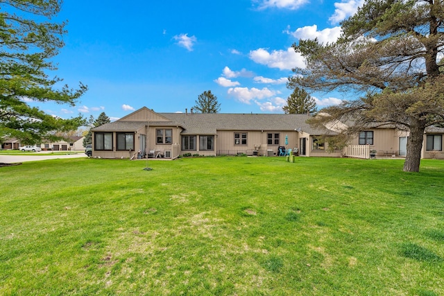 rear view of property featuring a shingled roof and a yard