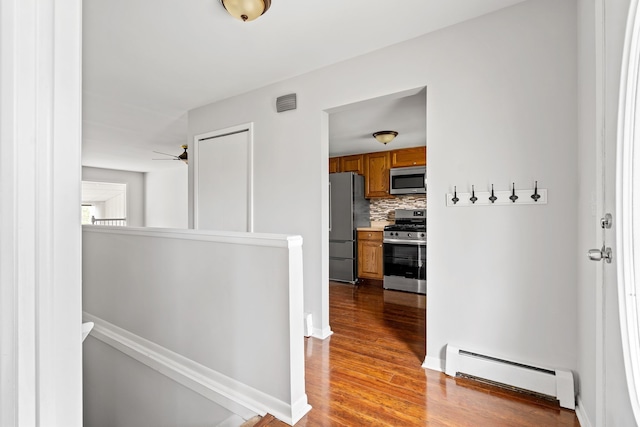 corridor with baseboards, baseboard heating, wood finished floors, and an upstairs landing