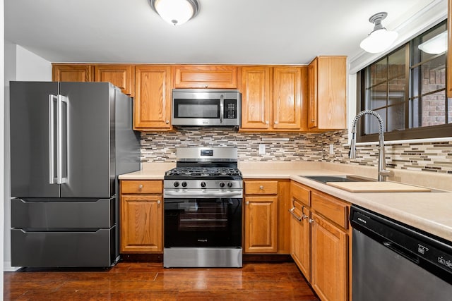 kitchen featuring decorative backsplash, dark wood-style flooring, appliances with stainless steel finishes, a sink, and light countertops