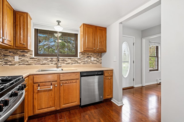 kitchen with dark wood-style flooring, light countertops, a sink, appliances with stainless steel finishes, and backsplash