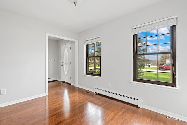 unfurnished room with baseboards, wood finished floors, and a baseboard radiator