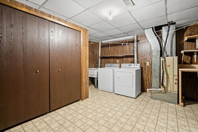 clothes washing area with separate washer and dryer, laundry area, light floors, and wooden walls