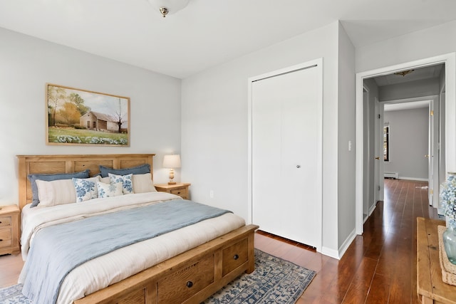 bedroom with a closet, baseboards, baseboard heating, and hardwood / wood-style floors