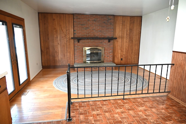 unfurnished living room with visible vents, baseboards, wooden walls, and a fireplace
