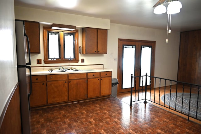 kitchen featuring freestanding refrigerator, light countertops, brown cabinets, french doors, and a sink