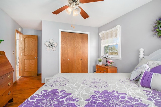 bedroom with a ceiling fan, visible vents, wood finished floors, and a closet