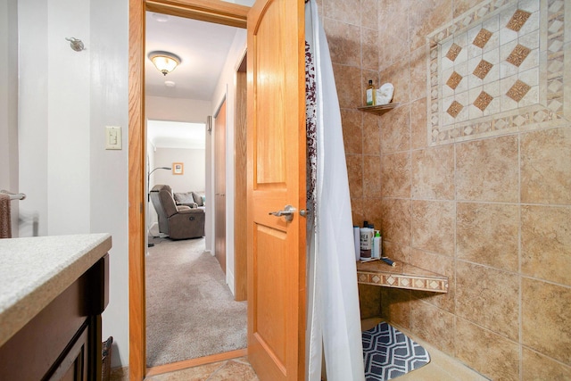 full bath with a tile shower and vanity