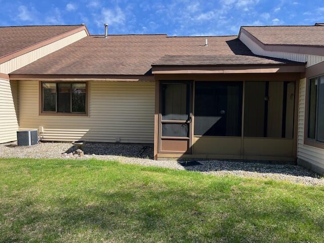 rear view of property with a lawn, roof with shingles, cooling unit, and a sunroom