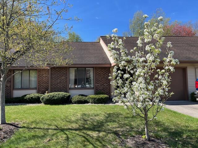 view of front of house featuring an attached garage, driveway, a front lawn, and brick siding
