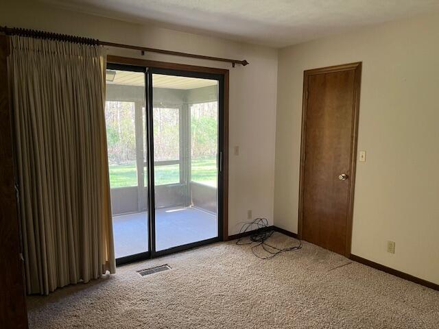 doorway featuring baseboards, light colored carpet, and visible vents