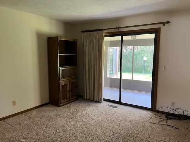 spare room with baseboards, visible vents, and light carpet