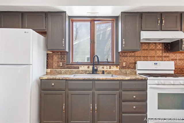 kitchen featuring white appliances, gray cabinetry, under cabinet range hood, and a sink
