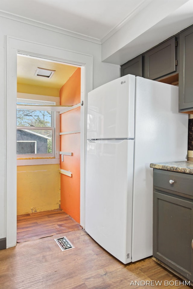 kitchen featuring gray cabinets, visible vents, crown molding, freestanding refrigerator, and light wood-style floors