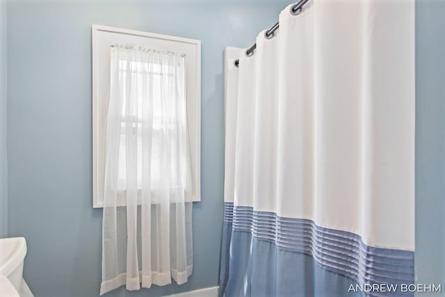 full bathroom featuring baseboards, a shower with shower curtain, and toilet