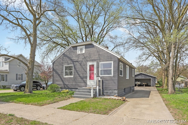 bungalow-style home featuring an outdoor structure, a garage, a front yard, and concrete driveway