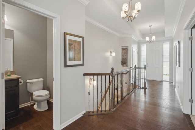 hall with an inviting chandelier, baseboards, a tray ceiling, hardwood / wood-style flooring, and an upstairs landing
