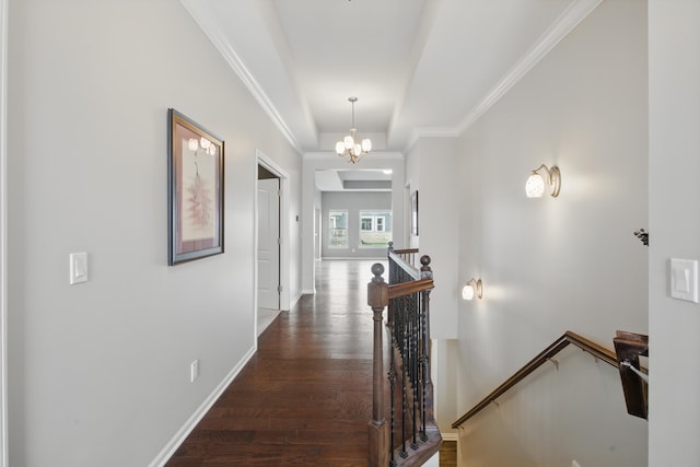 hallway with an upstairs landing, wood finished floors, baseboards, a notable chandelier, and ornamental molding
