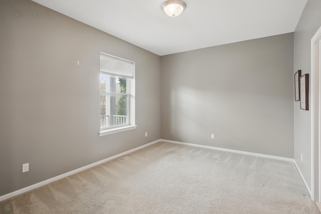 unfurnished room featuring baseboards and light carpet