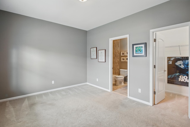 unfurnished bedroom featuring carpet flooring, baseboards, a walk in closet, and connected bathroom